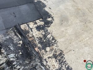 Ondergrond volledig bedekt met hardnekkige asfaltresten die gereinigd moeten worden.
