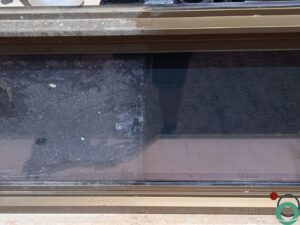 Geanodiseerd aluminium raam met cementresten, helft is schoon, de andere helft nog vuil