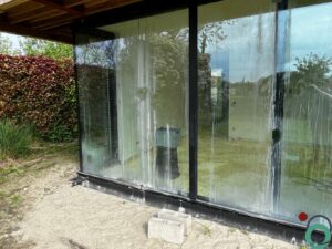 Aluminium venster met kalk- en cementstrepen door bouwwerken, te reinigen met gespecialiseerde technieken van Chemifor.