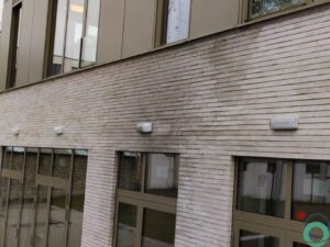 Lichte bakstenen gevel met zwarte roetaanslag