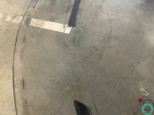 Betonnen vloer in een parkeergarage met zwarte rubbersporen in cirkelvormige patronen