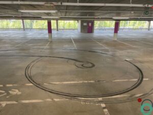 Betonnen vloer in een parkeergarage met zwarte rubbersporen in cirkelvormige patronen