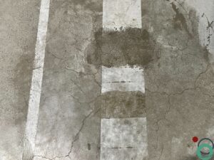 Betonnen vloer met gedeeltelijk verwijderde verfmarkering en zichtbare reiniging