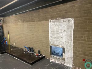 Bakstenen muur met zichtbare roetaanslag, deels gereinigd voor duidelijk contrast