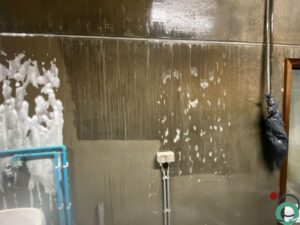 Binnenmuur met schuimlaag en afgetekende gereinigde zone na gebruik van Chemifor Roetverwijderaar