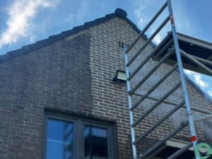 Gedeeltelijk gereinigde bakstenen gevel met zichtbaar verschil tussen vuil en schoon