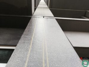Verticale betonnen gevel met fijne structuur en lichte kalkaanslag langs de voegen