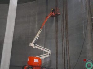 Verwijderen van donkere vervuilingsstromen op hoge betonnen wand met hoogtewerker