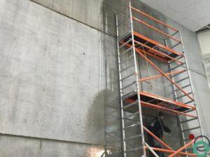 Reinigen van hoge betonwand met hogedrukspuit