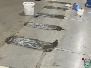 Verwijderen van oude markeringen op een industriële betonvloer met manuele technieken en reinigingsmateriaal