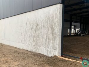 Prefab betongevel van een industrieel gebouw met duidelijke oliesporen en vervuiling door werfverkeer