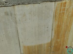 Betonnen wand met sterke roestvervuiling en zichtbaar gereinigd testvlak