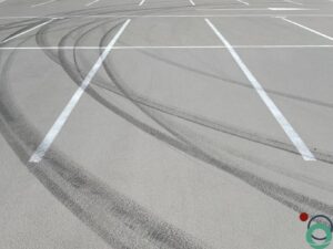 Lichte betonnen parkeerzone met opvallende zwarte rubbersporen van autobanden