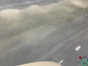 Nat gereinigde betonvloer met nog zichtbare bandensporen