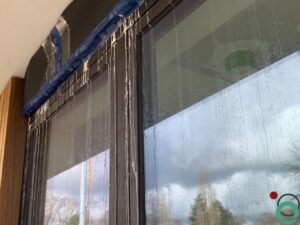 Witte kalk- en cementsporen zichtbaar op een zwart aluminium raamprofiel