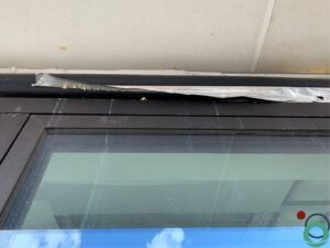Witte kalk- en cementsporen zichtbaar op een zwart aluminium raamprofiel