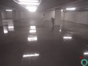 Dieptereiniging van de vloer in een ondergrondse parkeergarage met zichtbare vervuiling en reinigingssporen
