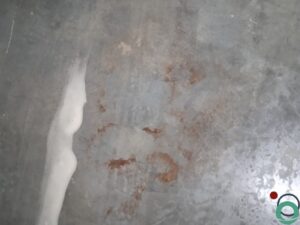 Dieptereiniging van de vloer in een ondergrondse parkeergarage met zichtbare vervuiling en reinigingssporen