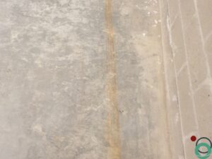 Metselmuur met verticale sporen van roestwater die vanaf het plafond naar beneden lopen