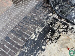 Donkere teervlekken zichtbaar op een stenen terrasoppervlak