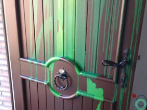 Groene verfspetters en druipers op een bakstenen muur en bestrating