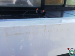 Wit balkon met verticale bruine uitlopers veroorzaakt door vervuiling of roestvorming