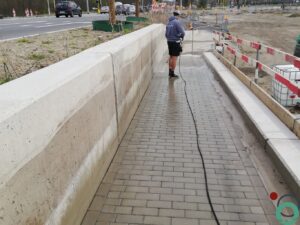 Zichtbetonnen keermuur vervuild met zwarte bitumenstroken die langs de wand uitlopen