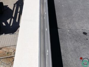 Wit balkon met verticale bruine uitlopers veroorzaakt door vervuiling of roestvorming