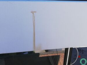 Wit balkon met verticale bruine uitlopers veroorzaakt door vervuiling of roestvorming