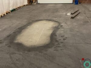Dieptereiniging van vervuilde vloer in een industriepand met zichtbare sporen en resten