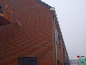Bakstenen gevel vervuild met cementstof na bouwwerken