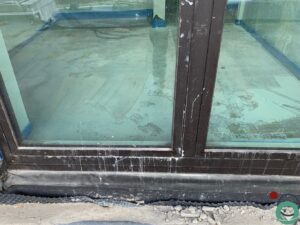 Witte kalk- en cementsporen zichtbaar op een zwart aluminium raamprofiel