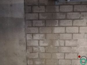 Metselmuur met verticale sporen van roestwater die vanaf het plafond naar beneden lopen