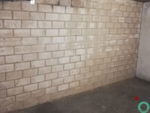 Metselmuur met verticale sporen van roestwater die vanaf het plafond naar beneden lopen