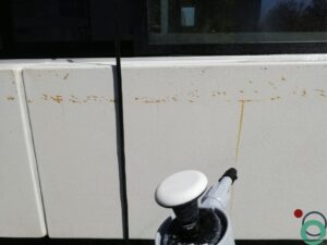 Wit balkon met verticale bruine uitlopers veroorzaakt door vervuiling of roestvorming