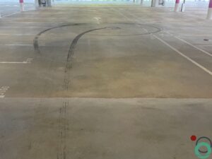 Zwarte rubbersporen zichtbaar op de vloer van een parkeergarage na intensief gebruik