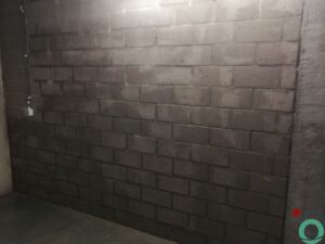 Metselmuur met verticale sporen van roestwater die vanaf het plafond naar beneden lopen