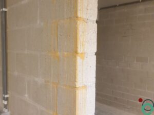 Metselmuur met verticale sporen van roestwater die vanaf het plafond naar beneden lopen