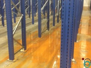 Uitgespreid roestwater veroorzaakt brede oranjebruine verkleuringen op een betonnen vloer in een industriële ruimte