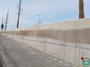 Zichtbetonnen keermuur vervuild met zwarte bitumenstroken die langs de wand uitlopen