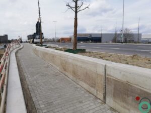 Zichtbetonnen keermuur vervuild met zwarte bitumenstroken die langs de wand uitlopen