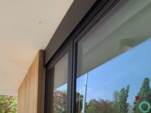 Witte kalk- en cementsporen zichtbaar op een zwart aluminium raamprofiel